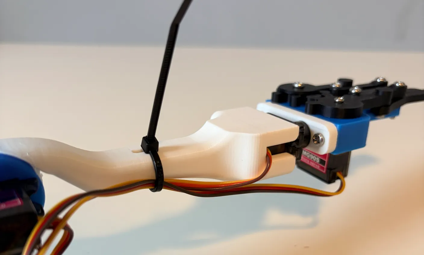 Robotic Arm build — Wire Management: Thread a zip tie through the white arm around the wrist and gripper wires.
