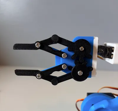 Close-up of the Robotic Arm Kit's black gripper jaws open above the blue rotating base
